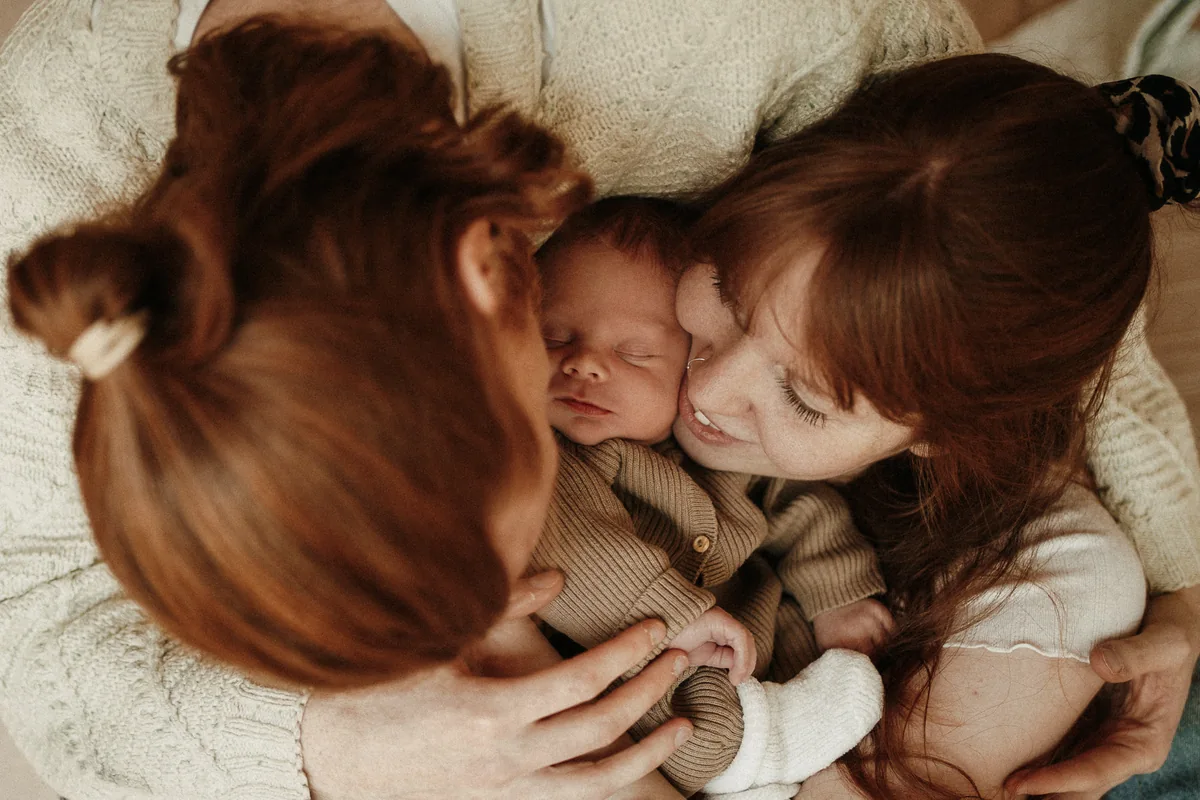 Ein Baby liegt geborgen zwischen seinen Eltern.