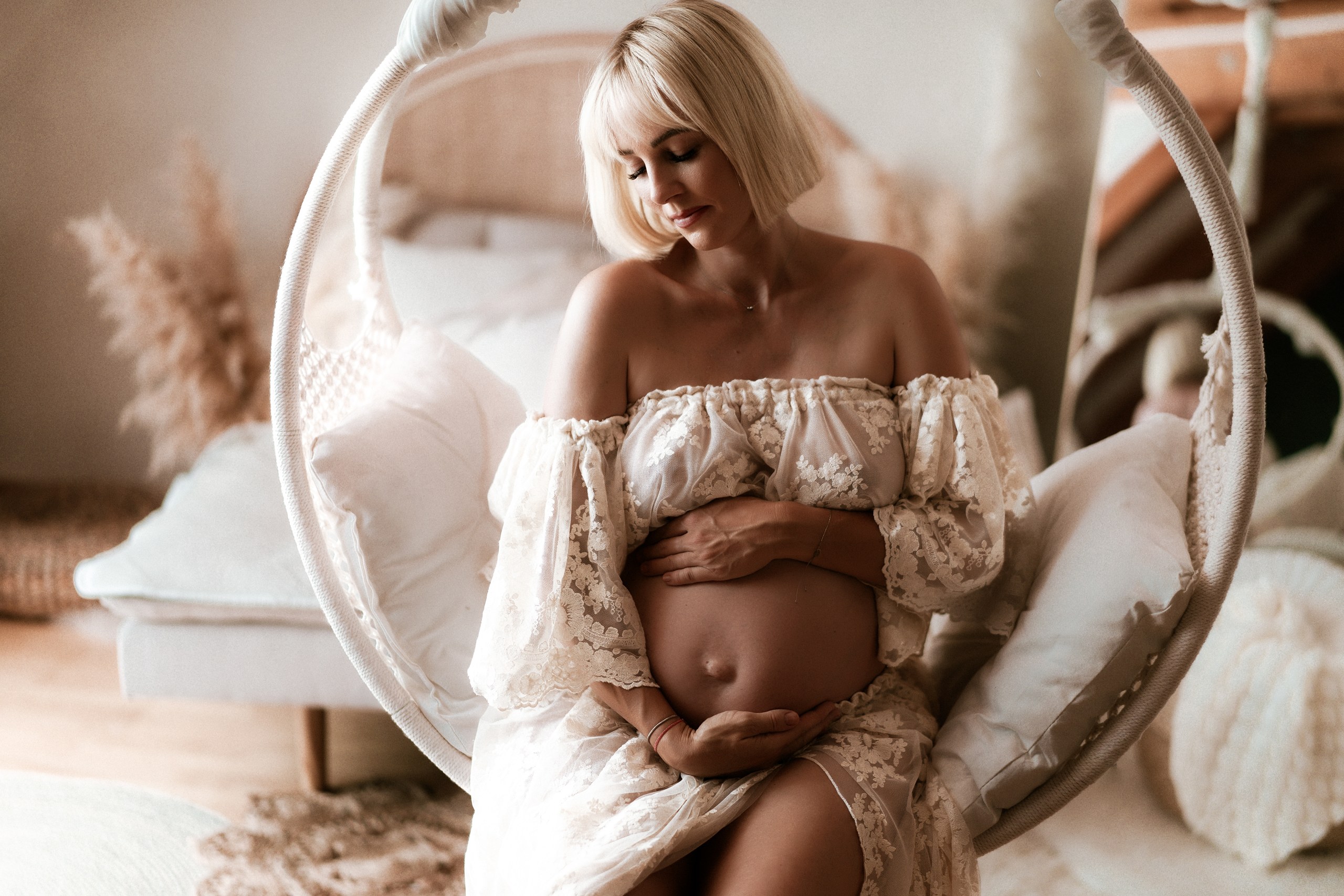 Eine werdende Mama hält ihren Babybauch im Hängesessel.