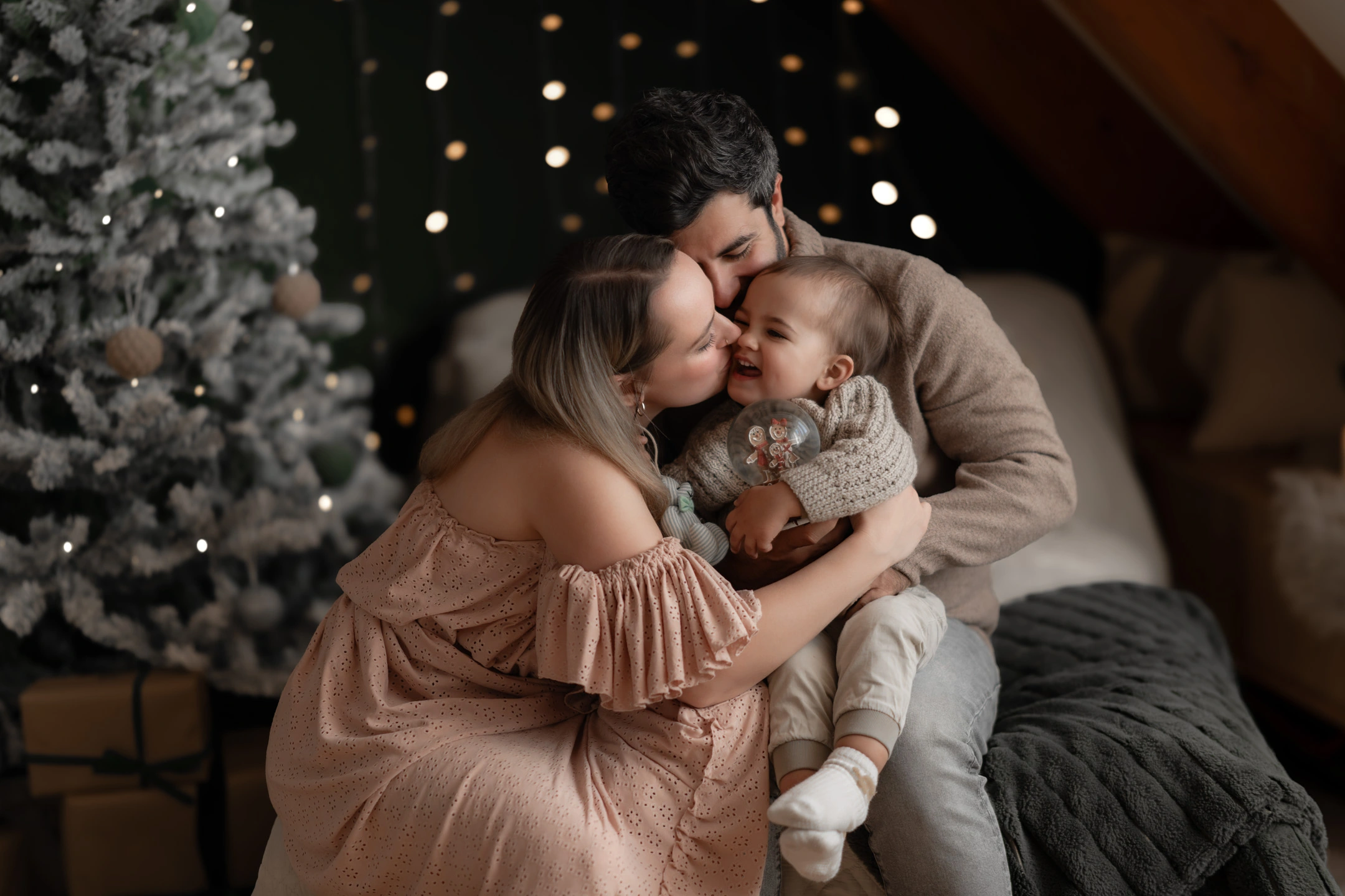 Lachendes Kind zwischen seinen Eltern in der Weihnachtskulisse