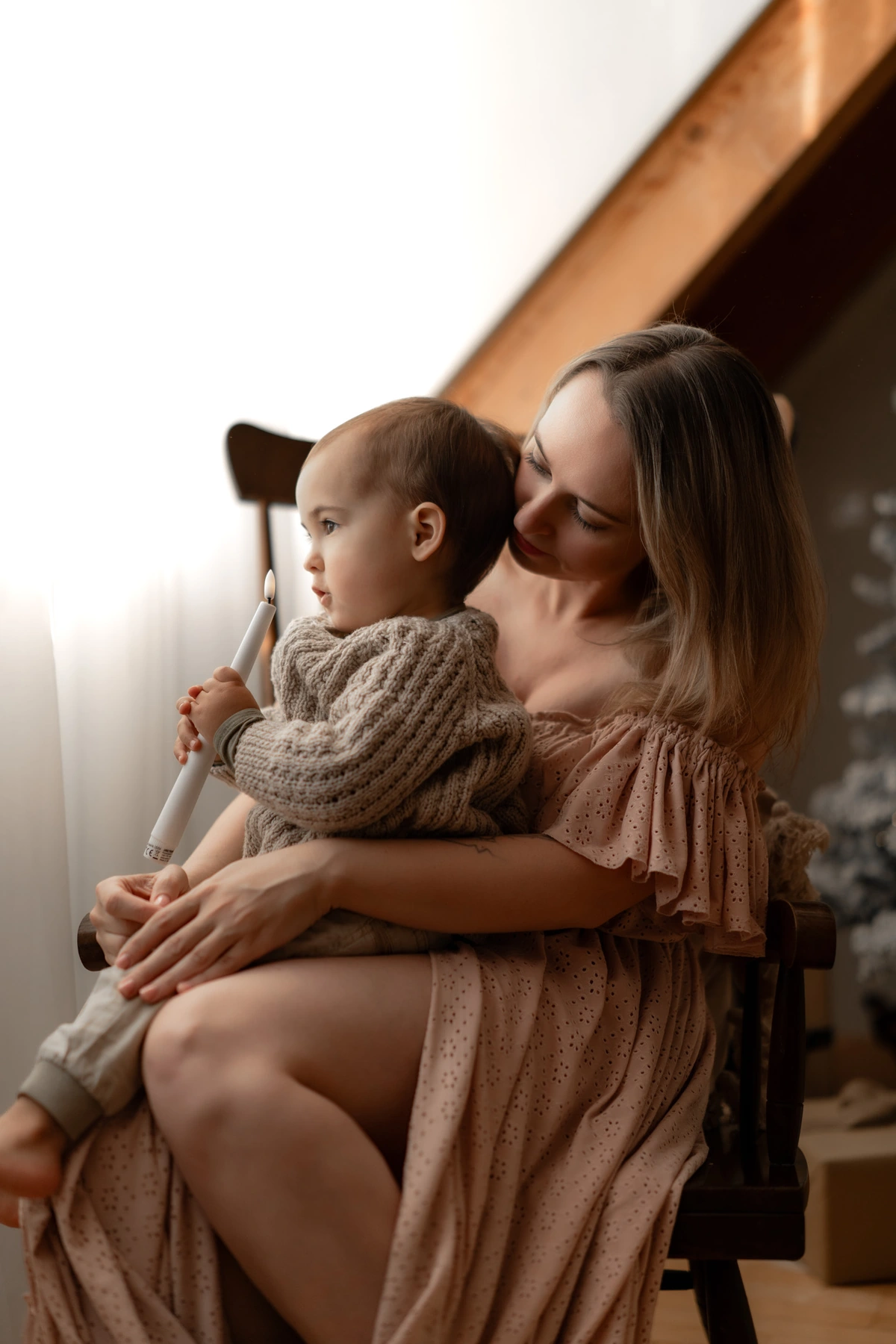 Mama und Kind kuscheln im Schaukelstuhl in der Weihnachtskulisse