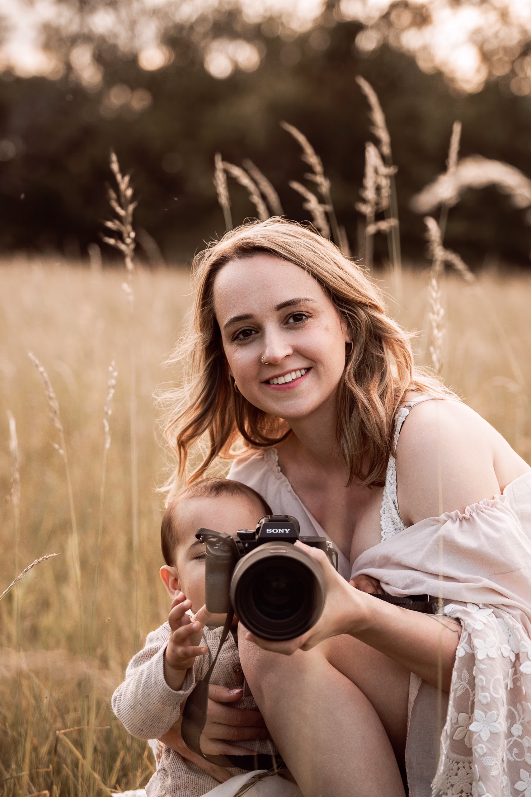 Verena mit einem Kind und ihrer Kamera auf einer Wiese.